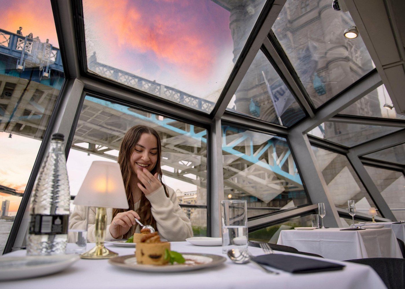 Jeune femme mangeant un gâteau sur un bateau qui passe sous le pont de Tower Bridge à Londres