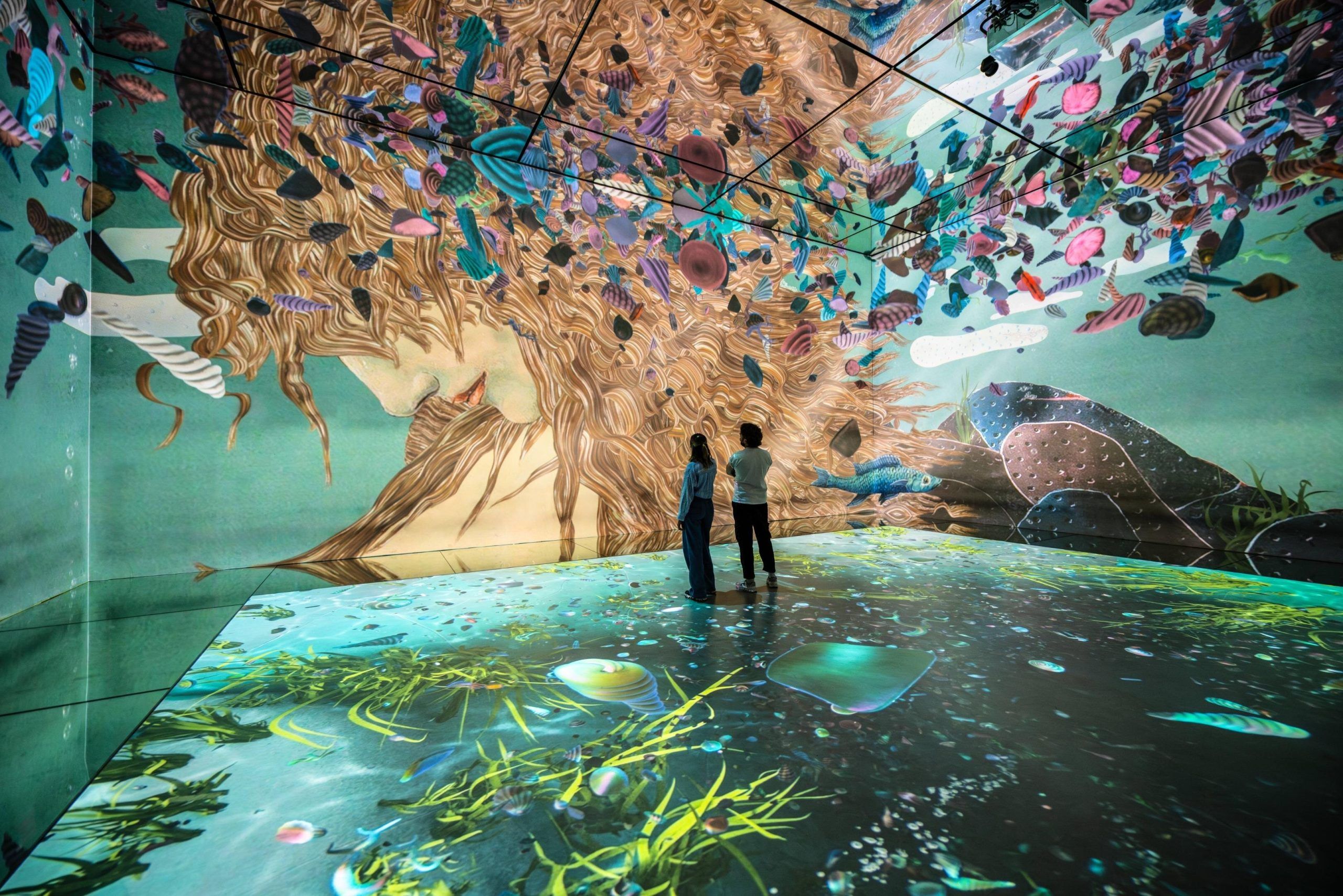 Couple devant une projection de L'Aube de Vénus par Thomas Lowinsky au musée Frameless de Londres